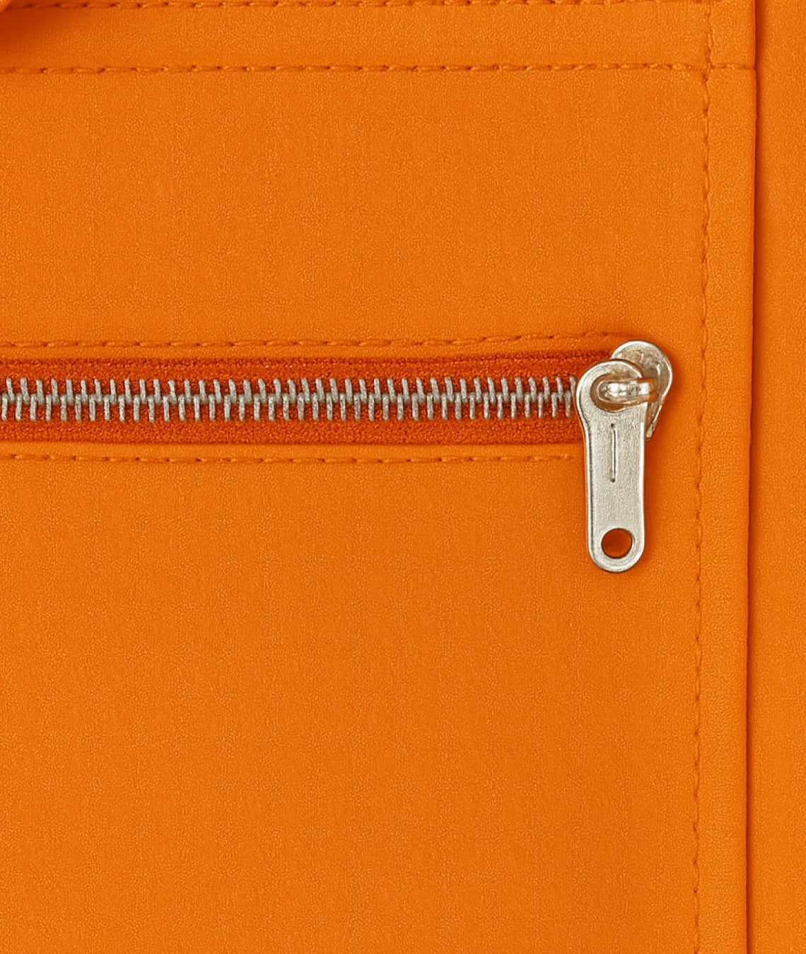 Close-up of an orange zipper on a textured surface